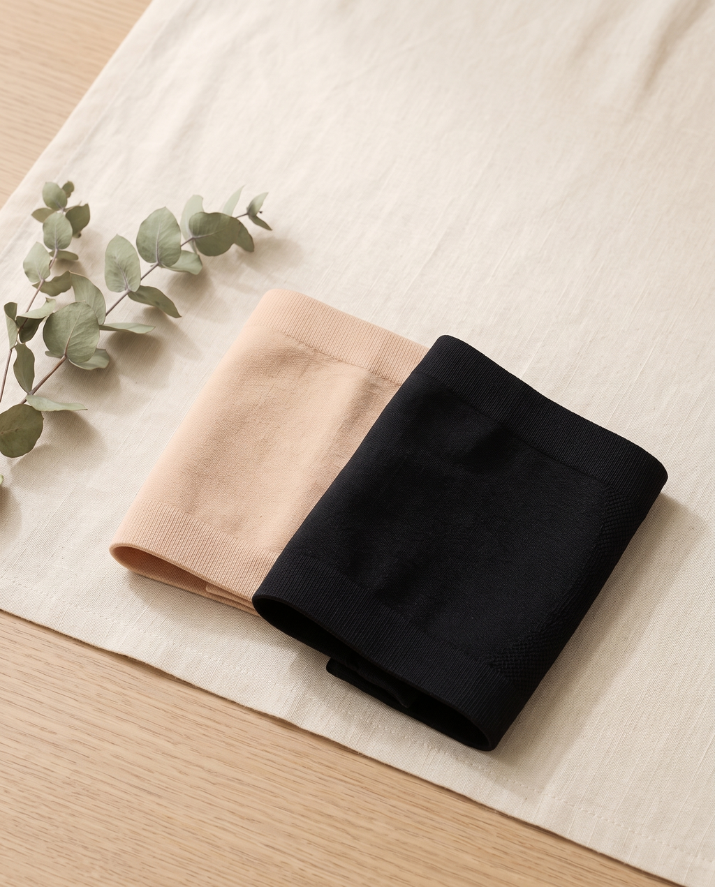 Softline Belly Bands in nude and black, folded on ivory linen