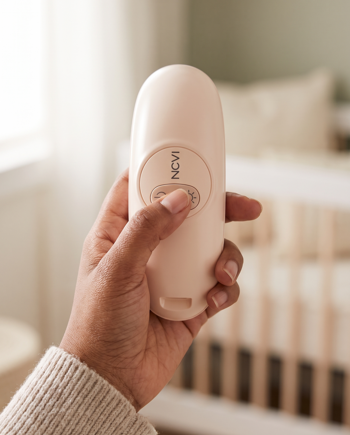 Hand holding the warming lactation massager with a thumb on the heat button